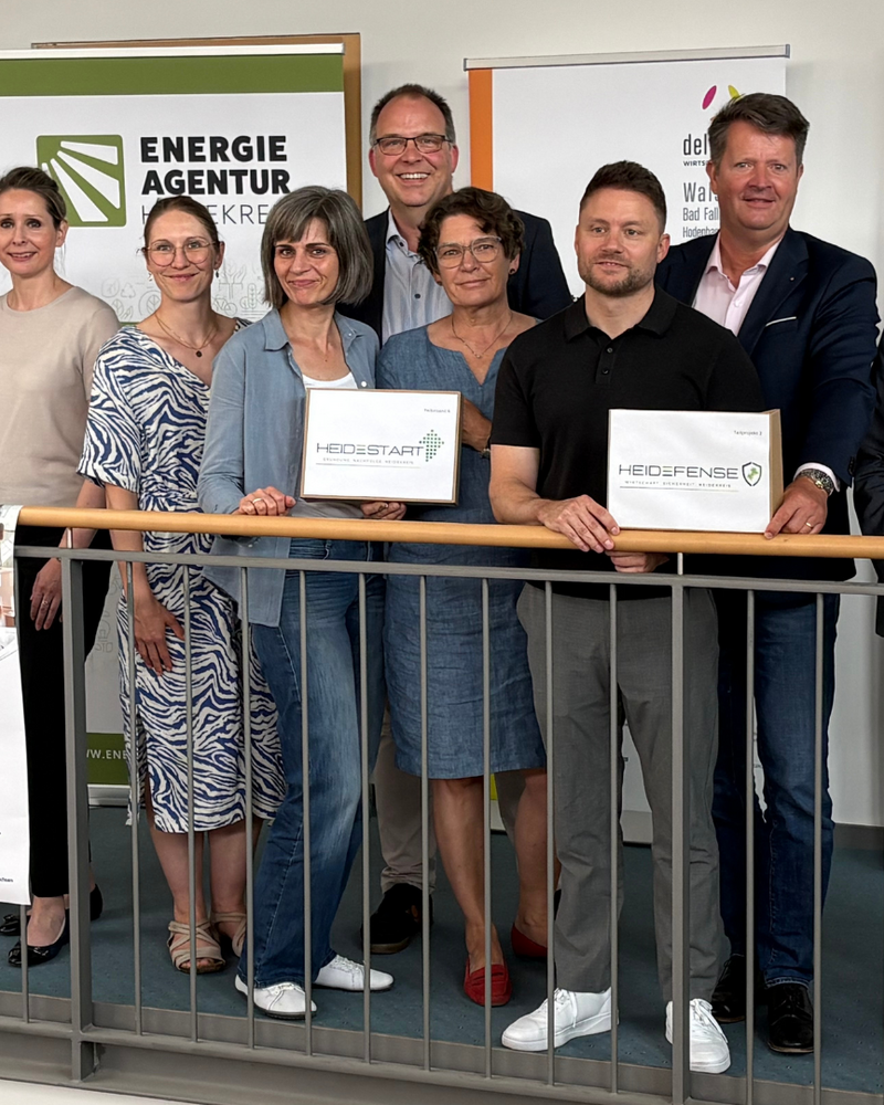 Gruppenfoto von elf Personen beim Projektauftakt TRENDS HK2030, drei davon halten Projektschilder: HeideStart, HeiDefense und TRENDS.