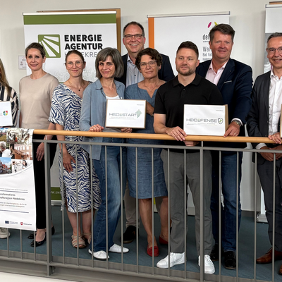 Gruppenfoto von elf Personen beim Projektauftakt TRENDS HK2030, drei davon halten Projektschilder: HeideStart, HeiDefense und TRENDS.