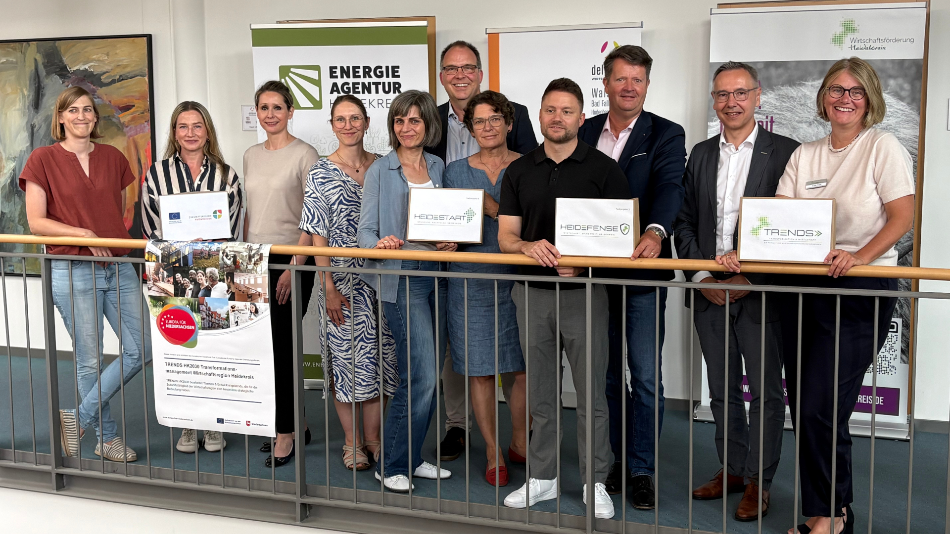 Gruppenfoto von elf Personen beim Projektauftakt TRENDS HK2030, drei davon halten Projektschilder: HeideStart, HeiDefense und TRENDS.