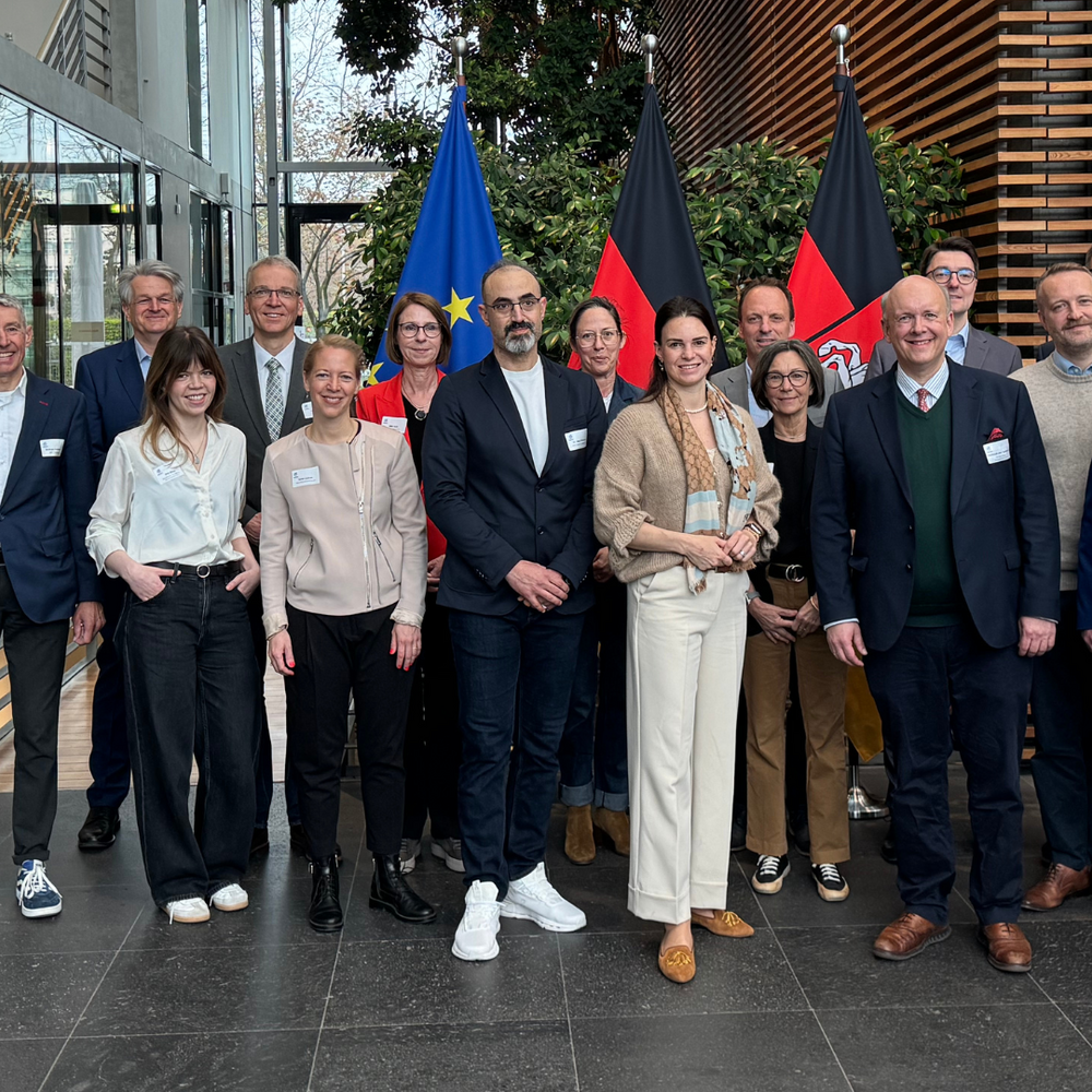 Gruppenfoto der Teilnehmenden des dritten H2.N.O.N-Hauptstadtfrühstücks am 14. April 2026 in der Vertretung des Landes Niedersachsen beim Bund in Berlin. Vor EU-Fahne und Deutschlandfahne versammeln sich rund 20 Vertreterinnen und Vertreter aus Wirtschaft, Netzwerk und Politik zum gemeinsamen Austausch über den Markthochlauf der Wasserstoffwirtschaft.