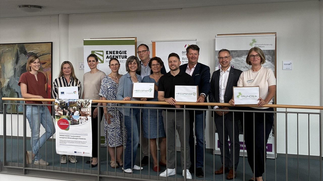 Elf Personen stehen nebeneinander für ein Gruppenfoto bei einem Pressetermin.