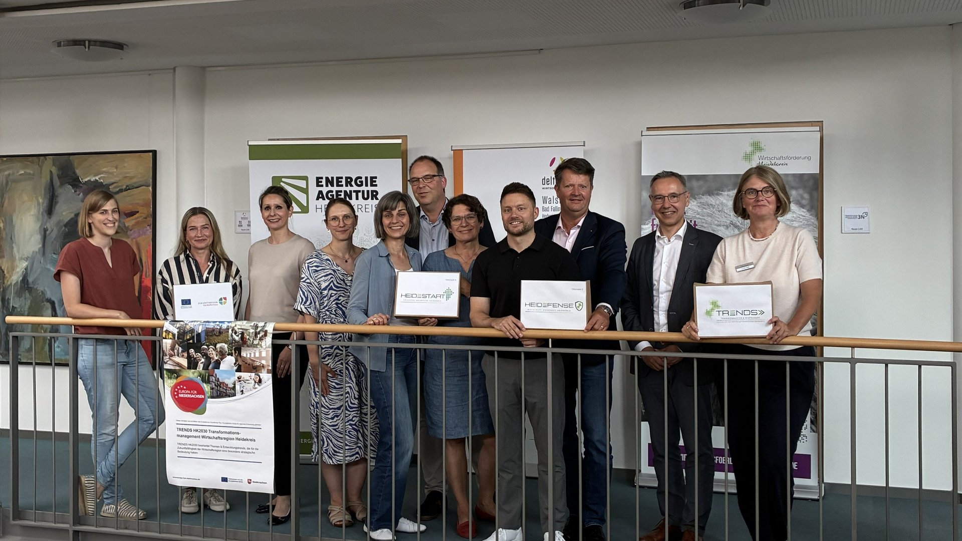 Elf Personen stehen nebeneinander für ein Gruppenfoto bei einem Pressetermin.