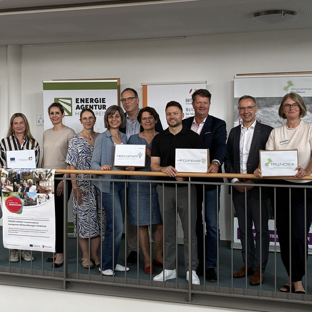 Elf Personen stehen nebeneinander für ein Gruppenfoto bei einem Pressetermin.