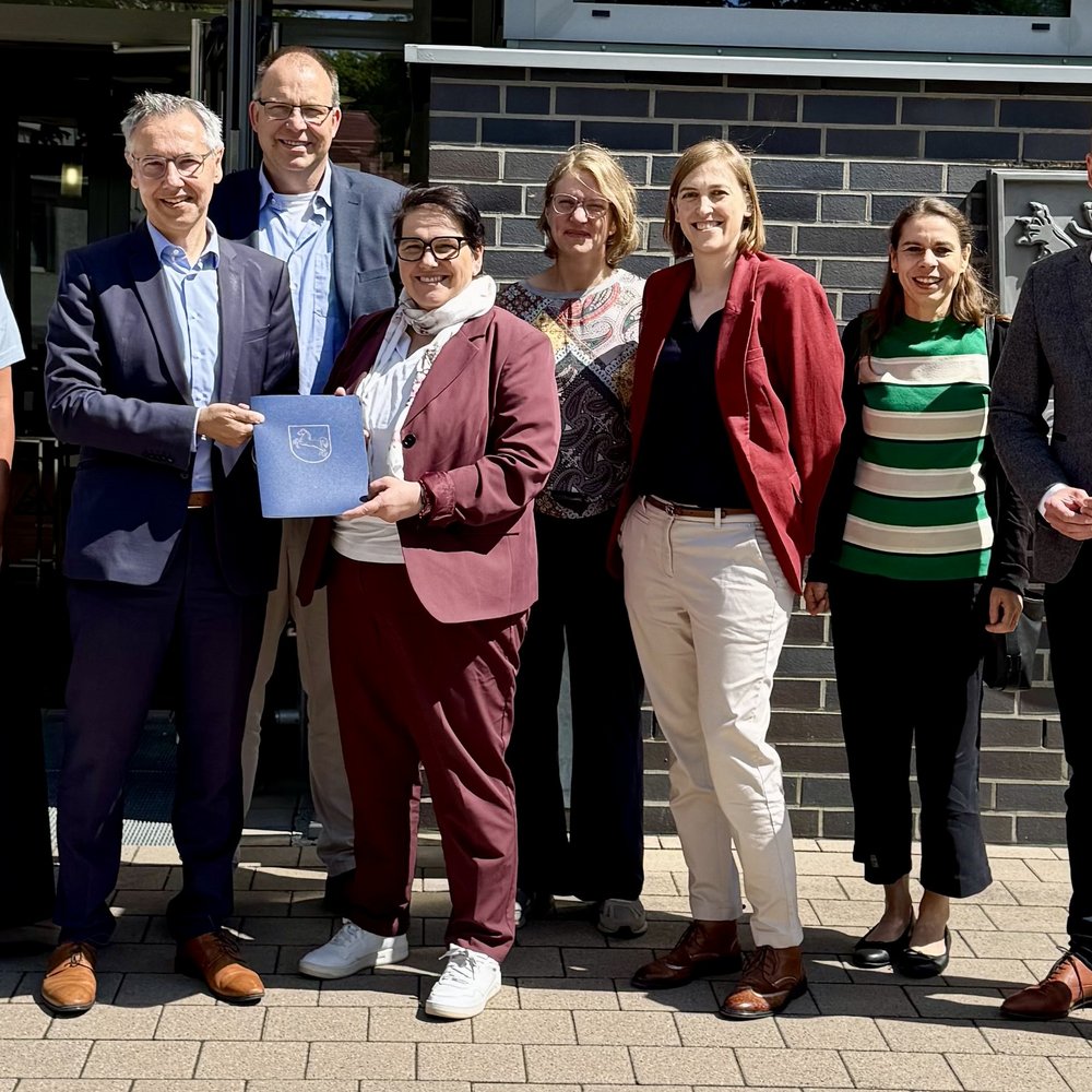 Das Foto ist ein Gruppenbild von 8 Personen bei der Übergabe eines Fördermittelbescheids. Zu sehen sind: Anke von Fintel (Landkreis Heidekreis), Landrat Jens Grote, Deltaland-Geschäftsführer Michael Krohn, Ministerin Melanie Walter, Dr. Theresa Weinsziehr (Energieagentur Heidekreis), Cornelia von Zengen (Landkreis Heidekreis),  Stefani Thomas (Amt für regionale Landesentwicklung), Sebastian Zinke (Mitglied des Landtags)