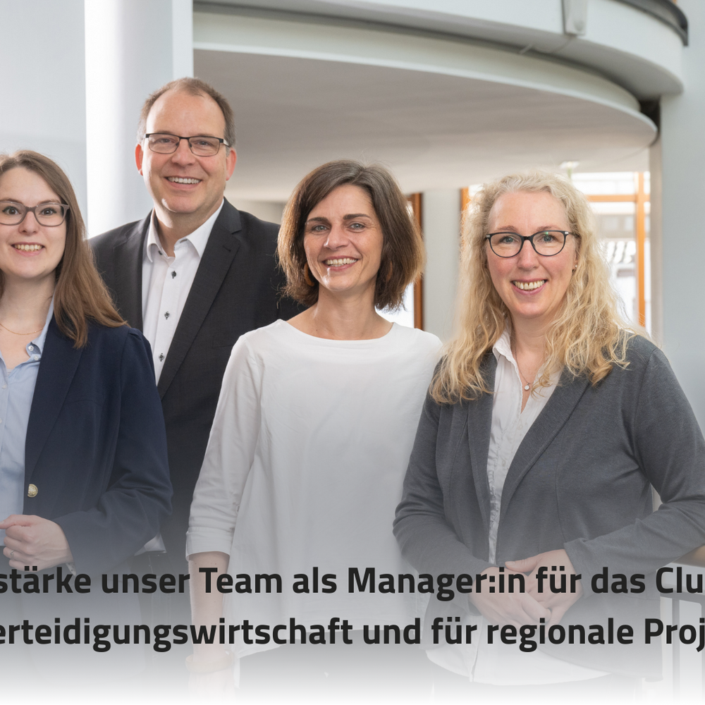 Das Bild zeigt vier Personen in einem modernen Büroumfeld, die freundlich in die Kamera lächeln. Im Vordergrund steht der Text "Verstärke unser Team als Manager:in für das Cluster Rüstungs-/Verteidigungswirtschaft und für regionale Projekte [m/w/d]".
